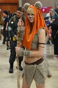 a woman dressed up in costume holding a stick and wearing a bear headdress