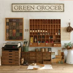 an old typewriter sitting on top of a wooden desk in front of a green grocer sign