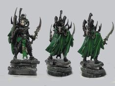 three painted warhammers with green cloaks and black swords on their arms, standing next to each other