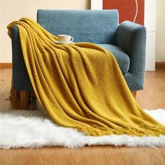 a blue couch with a yellow blanket on it and a white rug in front of it