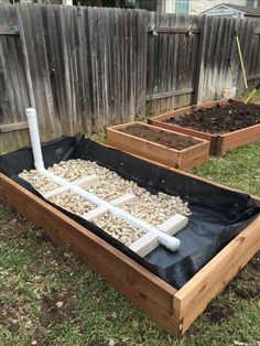 three wooden raised garden beds filled with dirt and rocks