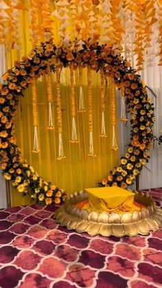 an arrangement of yellow flowers on a table in front of a curtain with tassels hanging from it