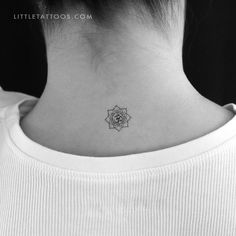 a woman's neck with a small flower tattoo on the back of her neck