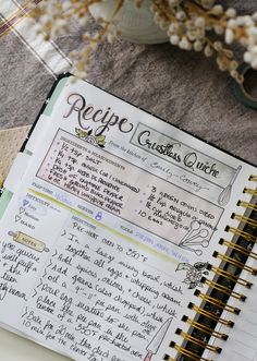 an open recipe book sitting on top of a table next to a vase with flowers