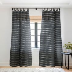 a black and white patterned curtain hanging in front of a window next to a rug