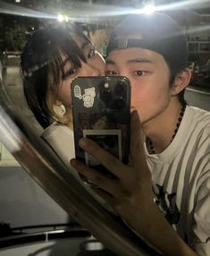 a man and woman taking a selfie in front of a mirror with their cell phone