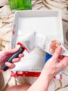 a person is painting a white box with red and blue paint on it while holding a brush