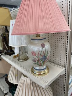 a lamp sitting on top of a white shelf next to a pink lampshade