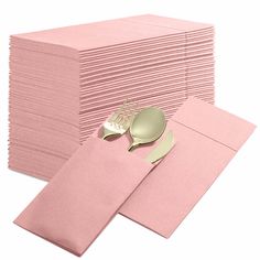 a stack of pink napkins with gold spoon and fork