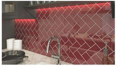 a kitchen with red and white tiles on the backsplash, stainless steel faucet