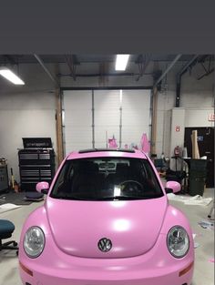 a pink vw beetle parked in a garage