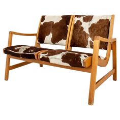 a brown and white cow print couch with wooden frame, armrests and back rest