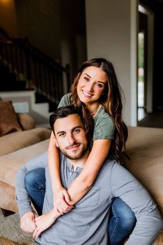 a man sitting on top of a woman's back while they both smile at the camera