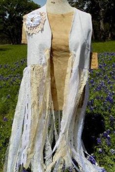 Shabby Festival Fringe Vest.  I collect vintage lace then cut into strips about 36 inches long, layer and add more to give varying lengths of lace for more texture in the fringe.  The fringe is added to a rough 100% cotton fabric vest where I add a bit more...antique doily on the back and one on the left "lapel" area with a satin rosette and piece of jewelry. All items are handmade, so no two items will be identical. As well there may be a slight difference between real and perceived colors of an item due to the nature of an item or resolution of a monitor. For best results, tie the fringe together so it doesn't tangle to machine wash cold and hang dry. Do not iron on the designs or lettering.  Sizing: X-Small (0-2) 34" bust Small(4-6) 36" bust  Medium (8-10) 38" bust Large (12-14)  40 " b Long Layer, Fringe Festival, Fringe Vest, Western Vintage, Altered Couture, Texas Hill Country, Antique Lace, Flowy Tops, Upcycle Clothes