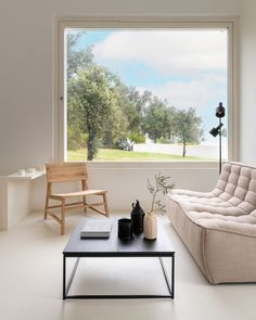 a living room filled with furniture and a large window overlooking a park outside the house