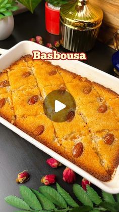 a cake in a pan on a table with flowers and leaves around it that says basabousa