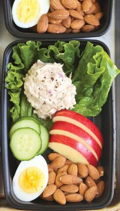 two plastic trays filled with different types of vegetables and fruits next to almonds