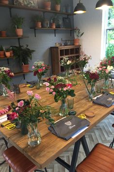 a wooden table topped with lots of vases filled with different types of flowers on top of it