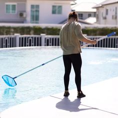 a woman holding a net while standing in front of a swimming pool with a paddle