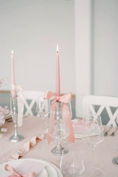 the table is set with pink candles and plates for two people to sit down at