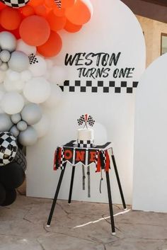 an orange and white cake on a table in front of a sign that says westton turns one