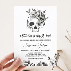 a person holding up a card with a skull and flowers on it, in front of a white background