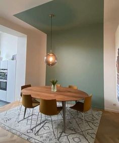 a dining room table with four chairs and a rug on the floor in front of it