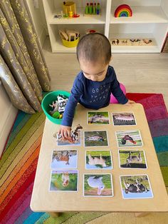 a toddler sitting at a table playing with pictures on the floor in front of him