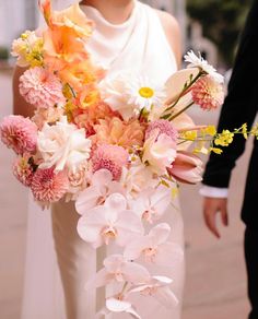 the bride and groom are walking down the street with their bouquets in hand,