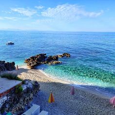 a beach with chairs and umbrellas next to the ocean