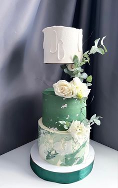 a three tiered cake with white flowers and greenery