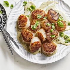 some scallops are on a white plate with sauce and green garnish