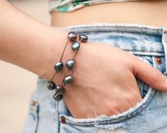 "We're obsessed with how versatile & durable our Tula Blue WRAPS are, & we know you will be too! You can wear your WRAP 4 ways: as a necklace, wrapped 3 times as a bracelet, wrapped twice as an anklet, or as a hairpiece. Don't be shy-- stack some more! Mix & match your wraps to make unique, eye-catching sets for every outfit. Rock them every way, every day. - Peacock Pearl Baroque Large (9-10mm)  - Signature hand-spun Tula Blue ROPE - 100% waterproof - Loop & puka shell closure - Standard length Handmade Adjustable Lariat Bracelets, Everyday Adjustable Fair Trade Jewelry, Adjustable Chain Bohemian Beaded Bracelets, Adjustable Bohemian Lariat Bracelets, Adjustable Bohemian Lariat Bracelet, Fair Trade Festival Bracelets, Blue Fair Trade Jewelry, Bohemian Fair Trade Bracelets, Fair Trade Bracelets For Gift