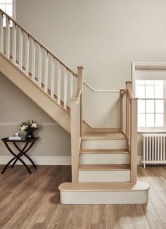 there is a white stair case next to a table with flowers on it and a window in the background