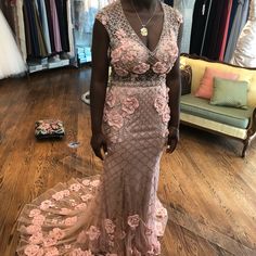 a woman standing in front of a rack of dresses with pink flowers on it's skirt