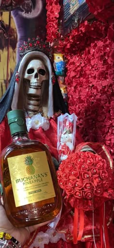 a bottle of booze sitting on top of a table next to a skull statue