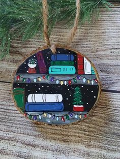 a christmas ornament hanging from a pine tree on a wooden table with books