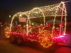 people are riding in the back of a truck decorated with christmas lights and decorations at night