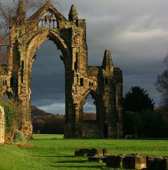 an old stone building sitting on top of a lush green field under a cloudy sky