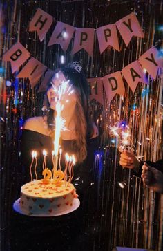 a woman standing in front of a birthday cake with lit candles