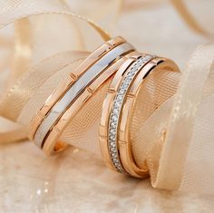 three different types of wedding rings on top of each other with diamonds in them and gold ribbons around the edges