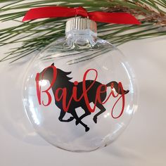 a glass ornament with a horse on it and the word bailey written in red