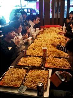 many people are sitting at a long table with food on it and one person is using his cell phone