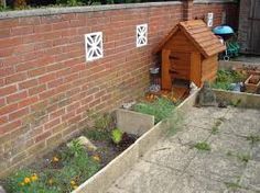 a dog house built into the side of a brick wall with flowers growing in it