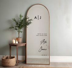 a large mirror sitting on top of a wooden floor next to a table and potted plant