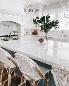 a kitchen with white counter tops and wicker chairs