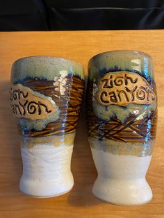 two ceramic mugs sitting on top of a wooden table