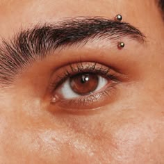 a man with piercings on his forehead looking at the camera while he has brown eyes