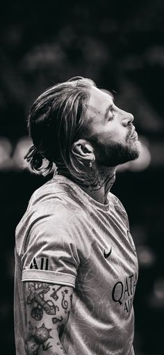 a man with long hair and tattoos on his face is looking up at the sky