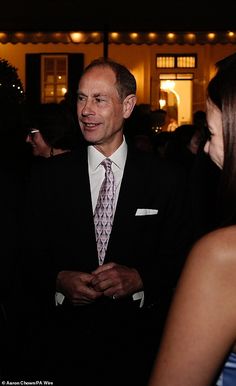 a man in a suit and tie standing next to a woman